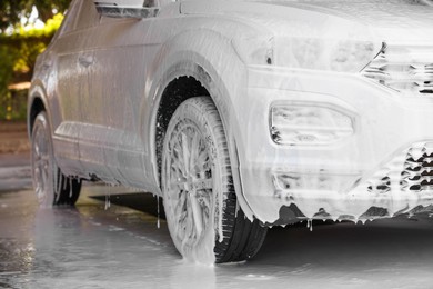 Photo of Auto covered with cleaning foam at outdoor car wash