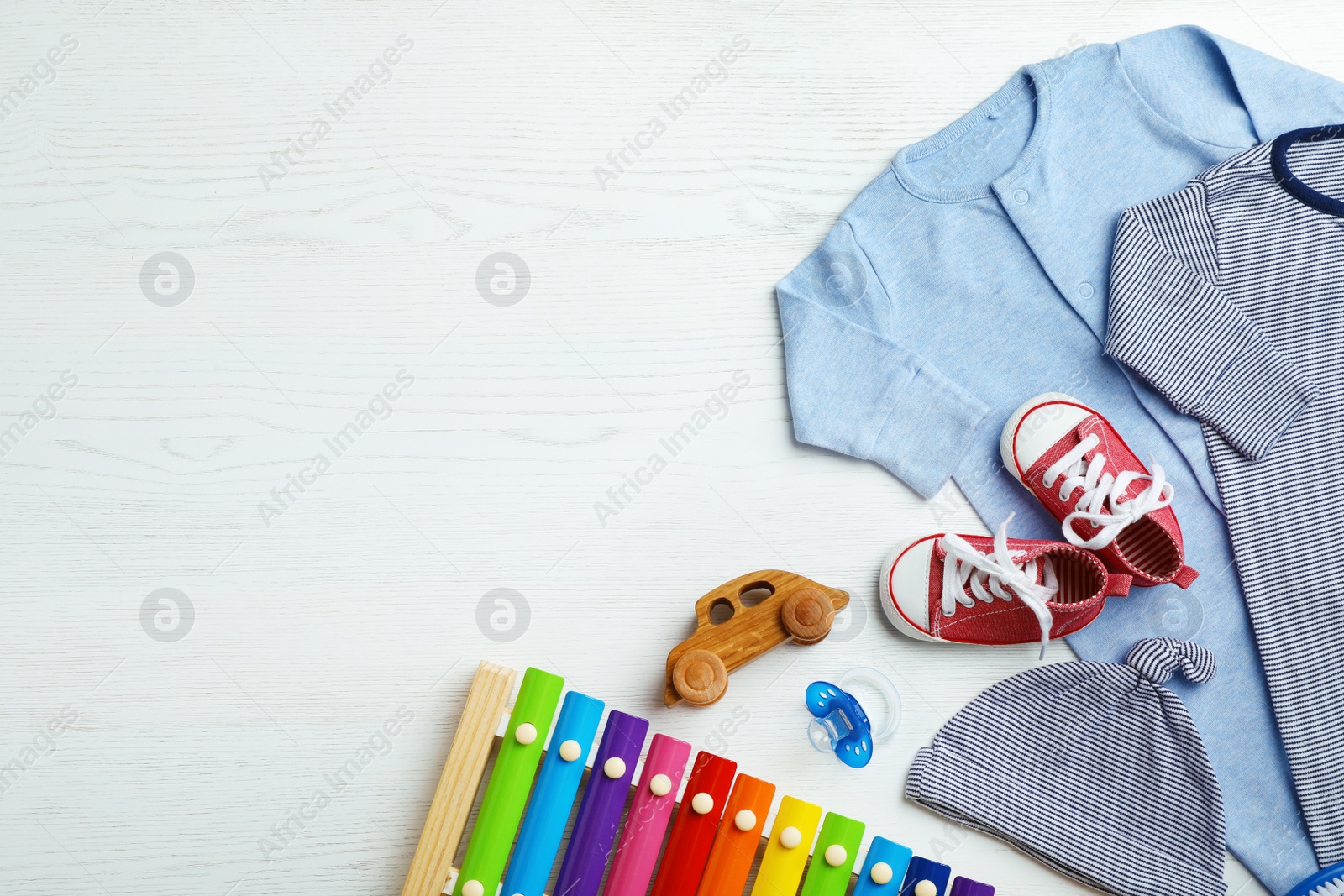 Photo of Flat lay composition with cute clothes and space for text on white wooden background. Baby accessories