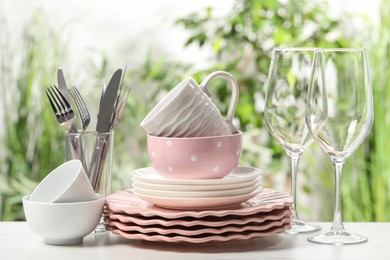 Photo of Beautiful ceramic dishware, glasses, cutlery and cup on white table outdoors