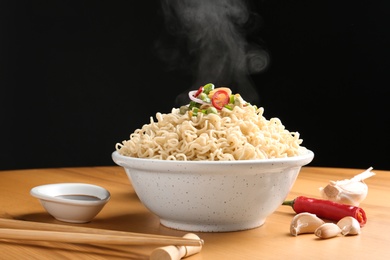 Bowl of hot noodles with vegetables and chopsticks served on table