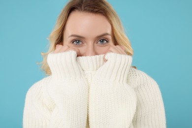 Photo of Beautiful woman in stylish warm sweater on light blue background