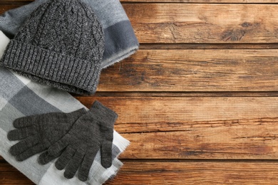 Stylish gloves, scarf and hat on wooden background, flat lay. Space for text