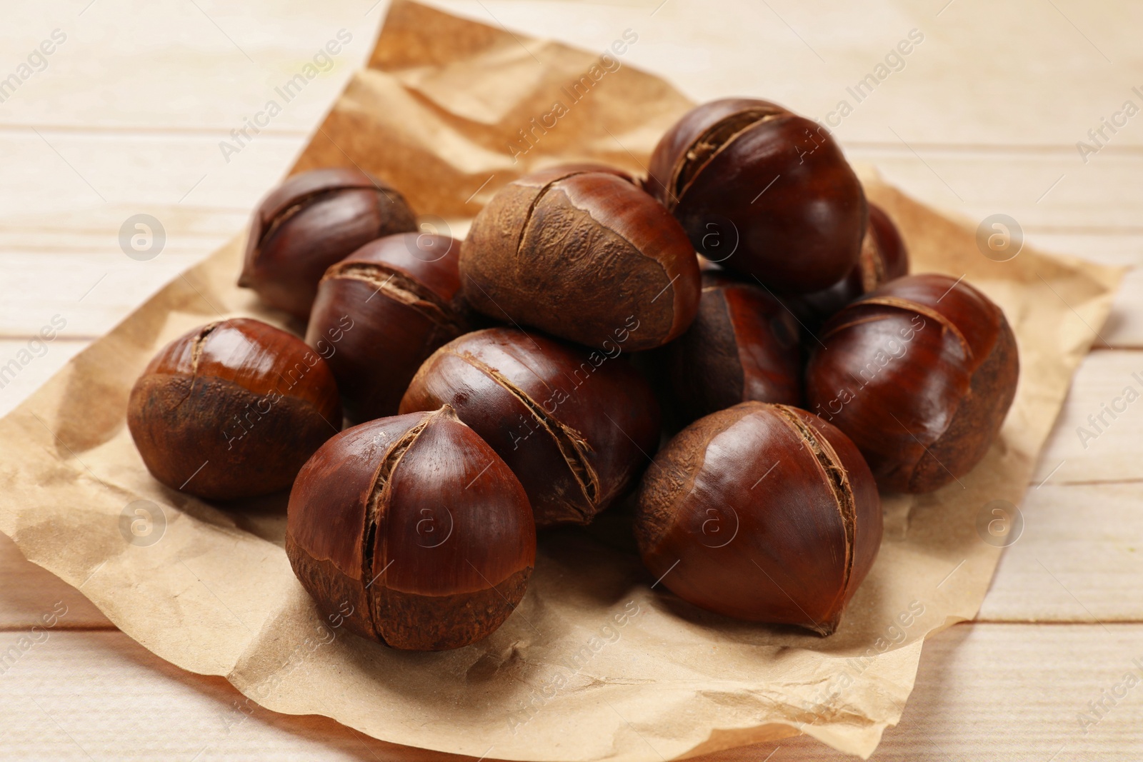 Photo of Roasted edible sweet chestnuts on wooden table, closeup