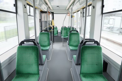 Photo of Public transport interior with comfortable green seats and handgrip handles