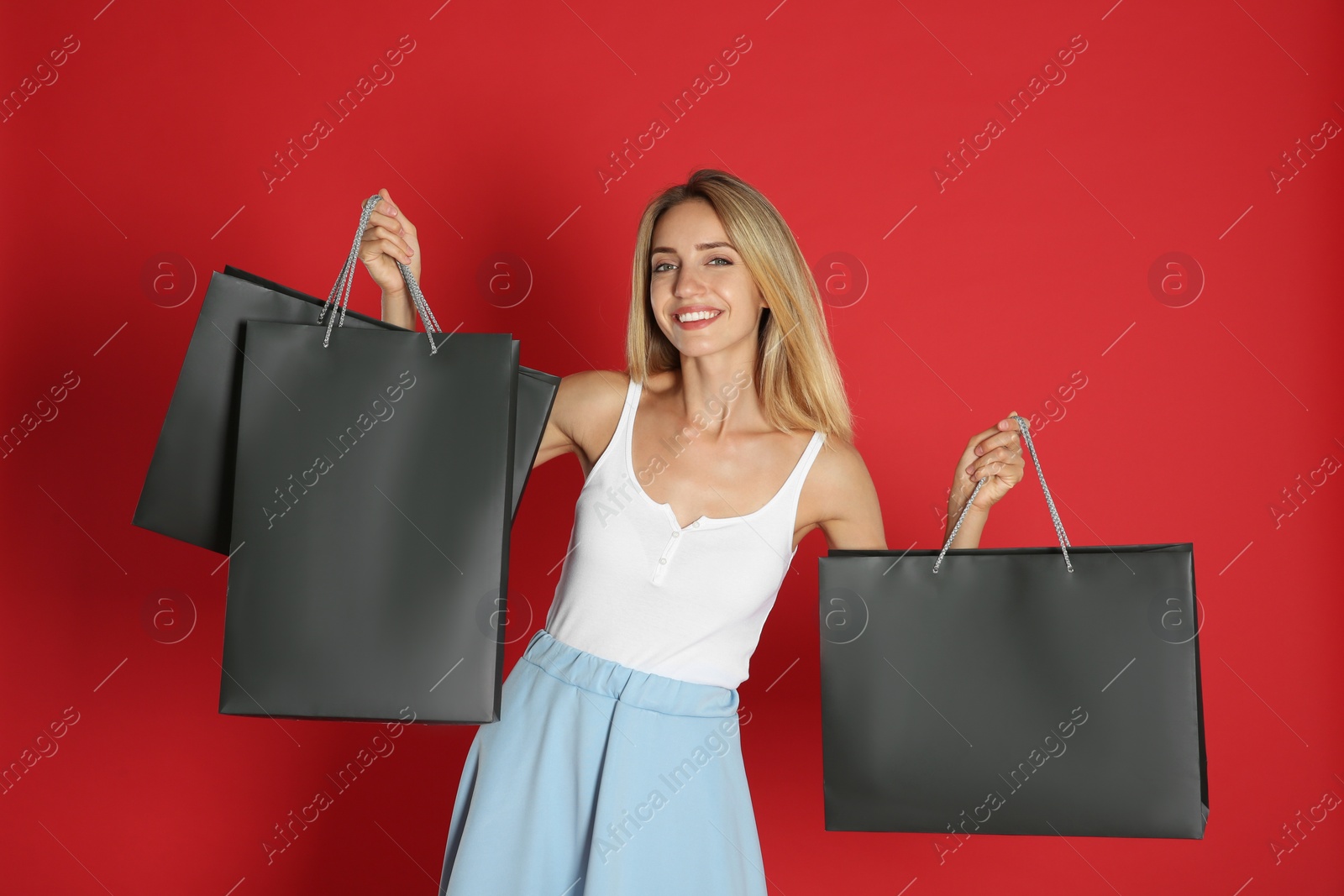 Photo of Happy young woman with shopping bags on red background. Black Friday Sale