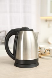 Photo of Modern electric kettle on table in kitchen