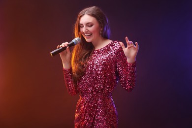 Emotional woman with microphone singing in color lights