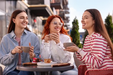 Photo of Happy friends talking and drinking coffee in outdoor cafe