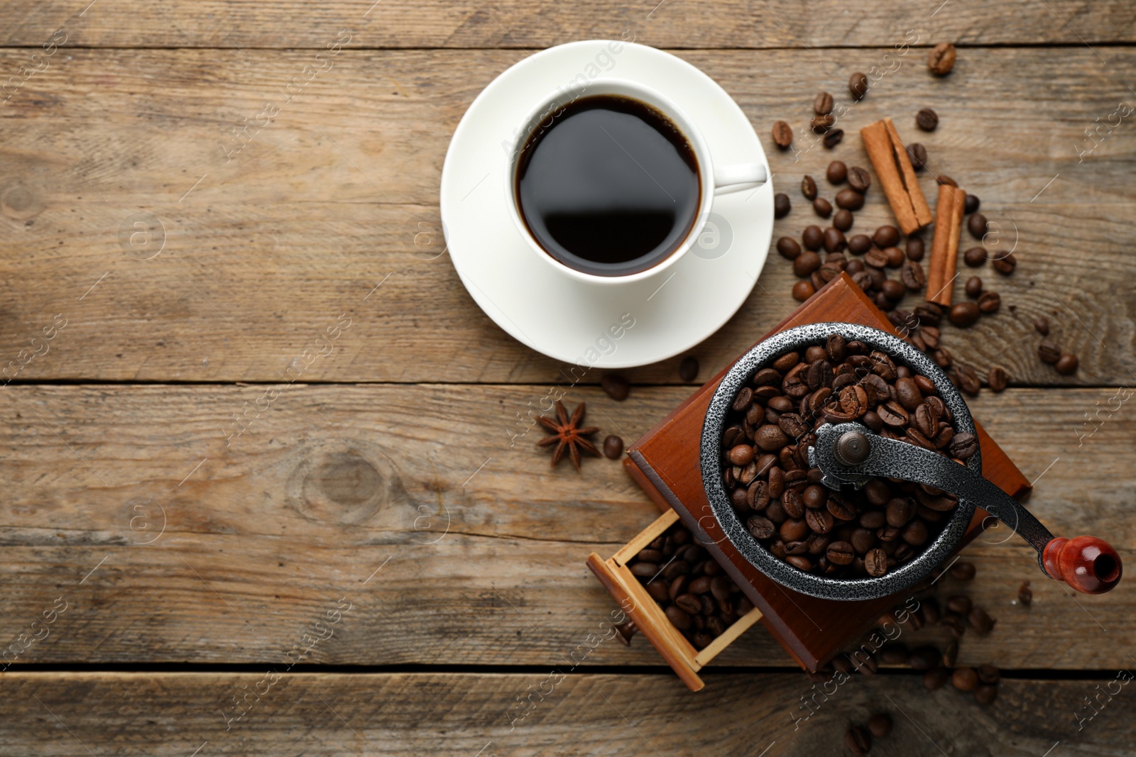 Photo of Vintage manual coffee grinder, beans and cup of drink on wooden table, flat lay. Space for text