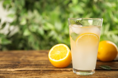 Photo of Cool freshly made lemonade in glass on wooden table. Space for text