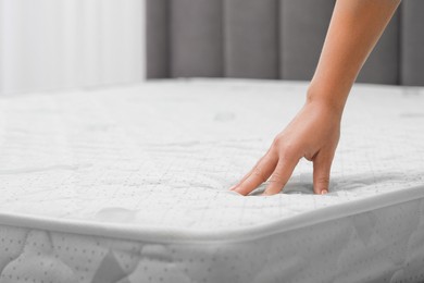 Photo of Woman touching new soft mattress indoors, closeup