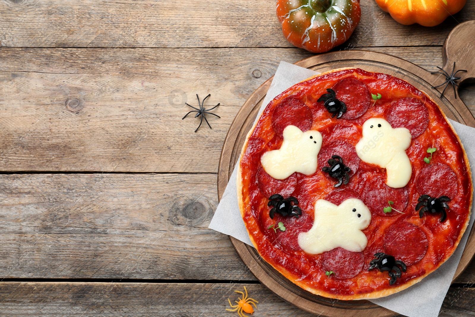 Photo of Cute Halloween pizza with ghosts and spiders served on wooden table, flat lay. Space for text