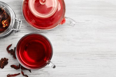 Photo of Delicious hibiscus tea and dry flowers on white wooden table, flat lay. Space for text