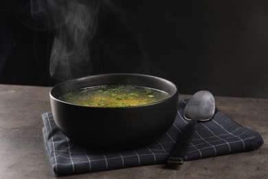 Photo of Delicious soup with parsley and spoon on grey table