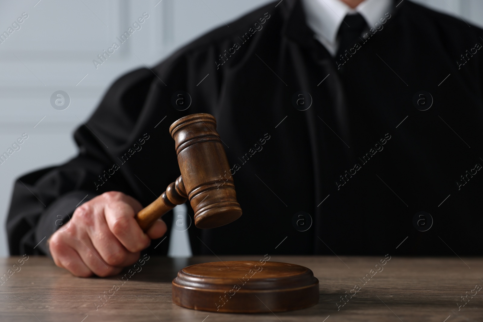 Photo of Judge with gavel sitting at wooden table, closeup