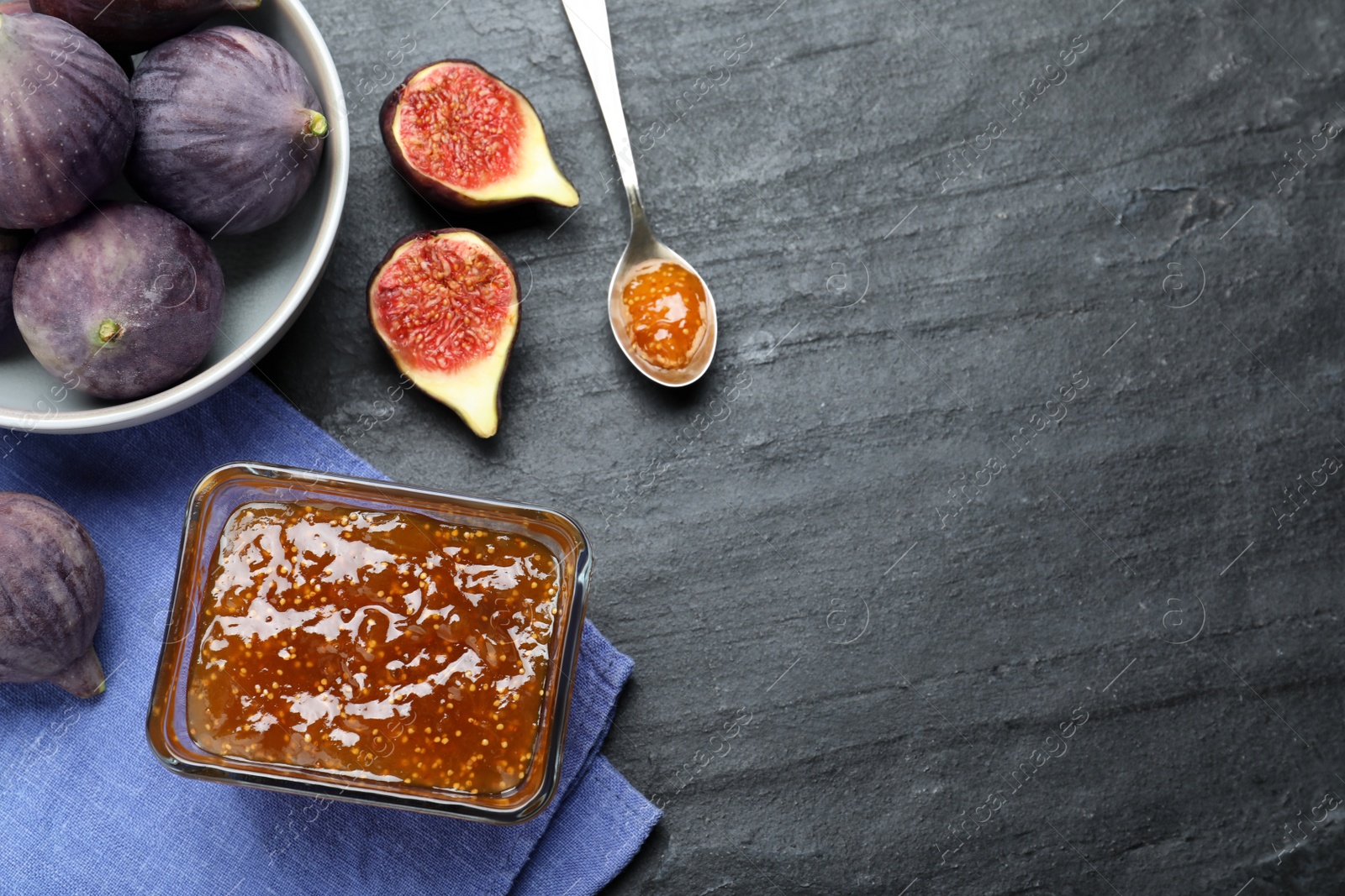 Photo of Delicious fig jam and fresh fruits on black table, flat lay. Space for text