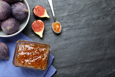 Photo of Delicious fig jam and fresh fruits on black table, flat lay. Space for text