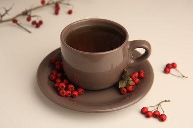 Photo of Brown cup with hawthorn tea and berries on beige table