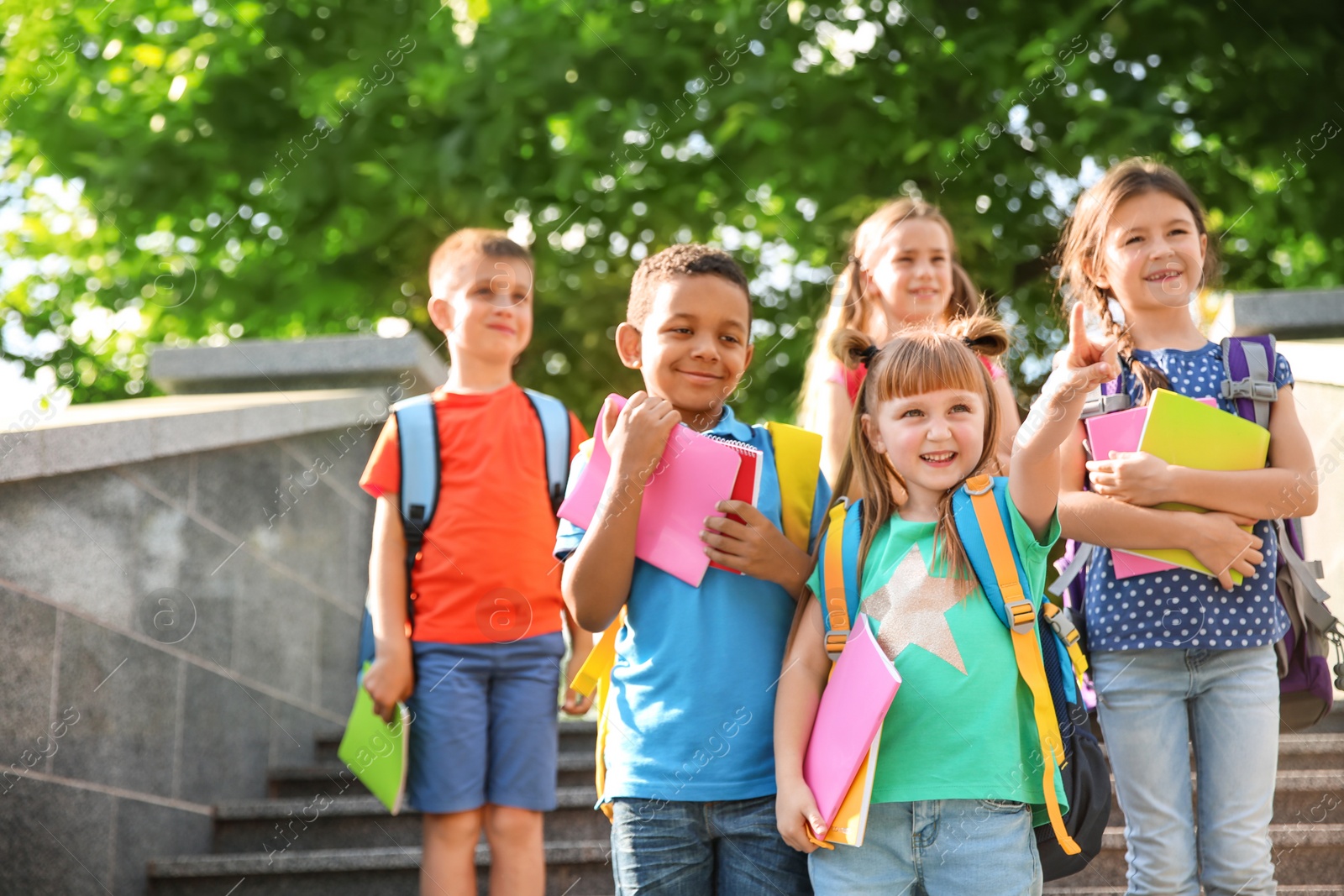 Photo of Cute little children with backpacks and notebooks outdoors. Elementary school