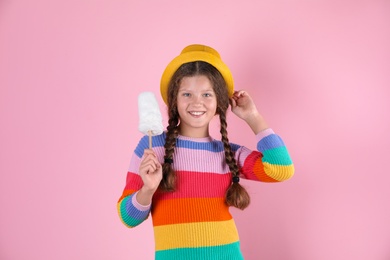 Little girl with cotton candy on color background