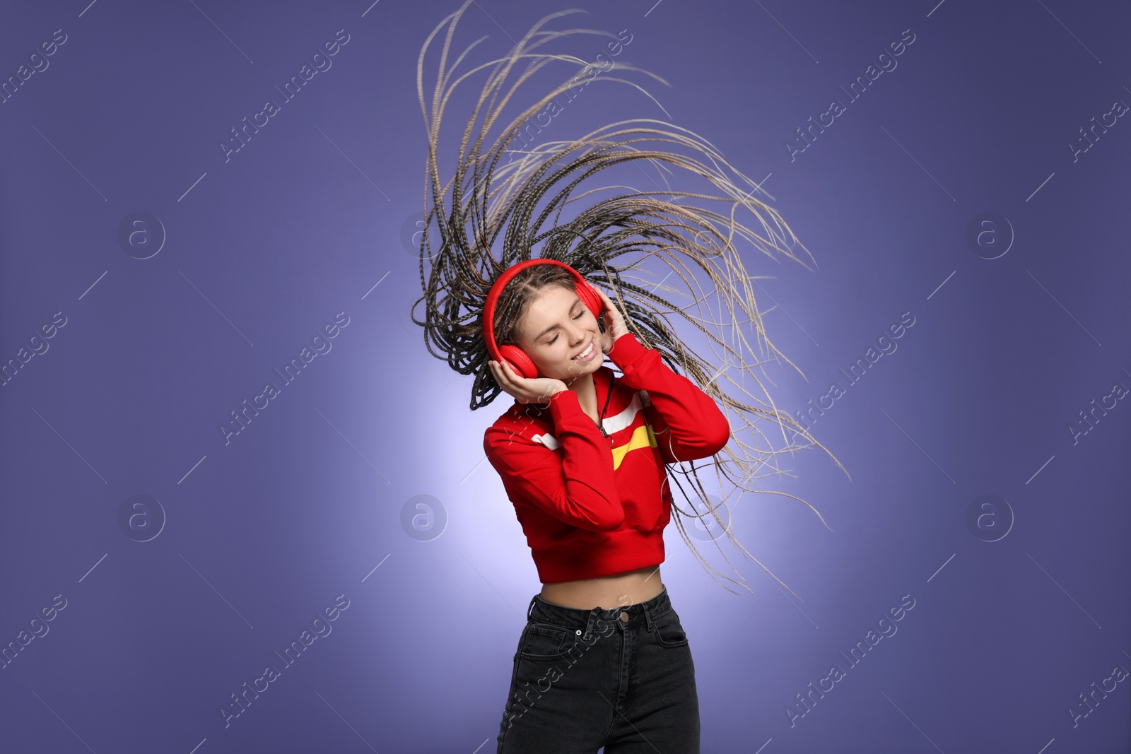 Photo of Beautiful woman with long african braids listening music on purple background