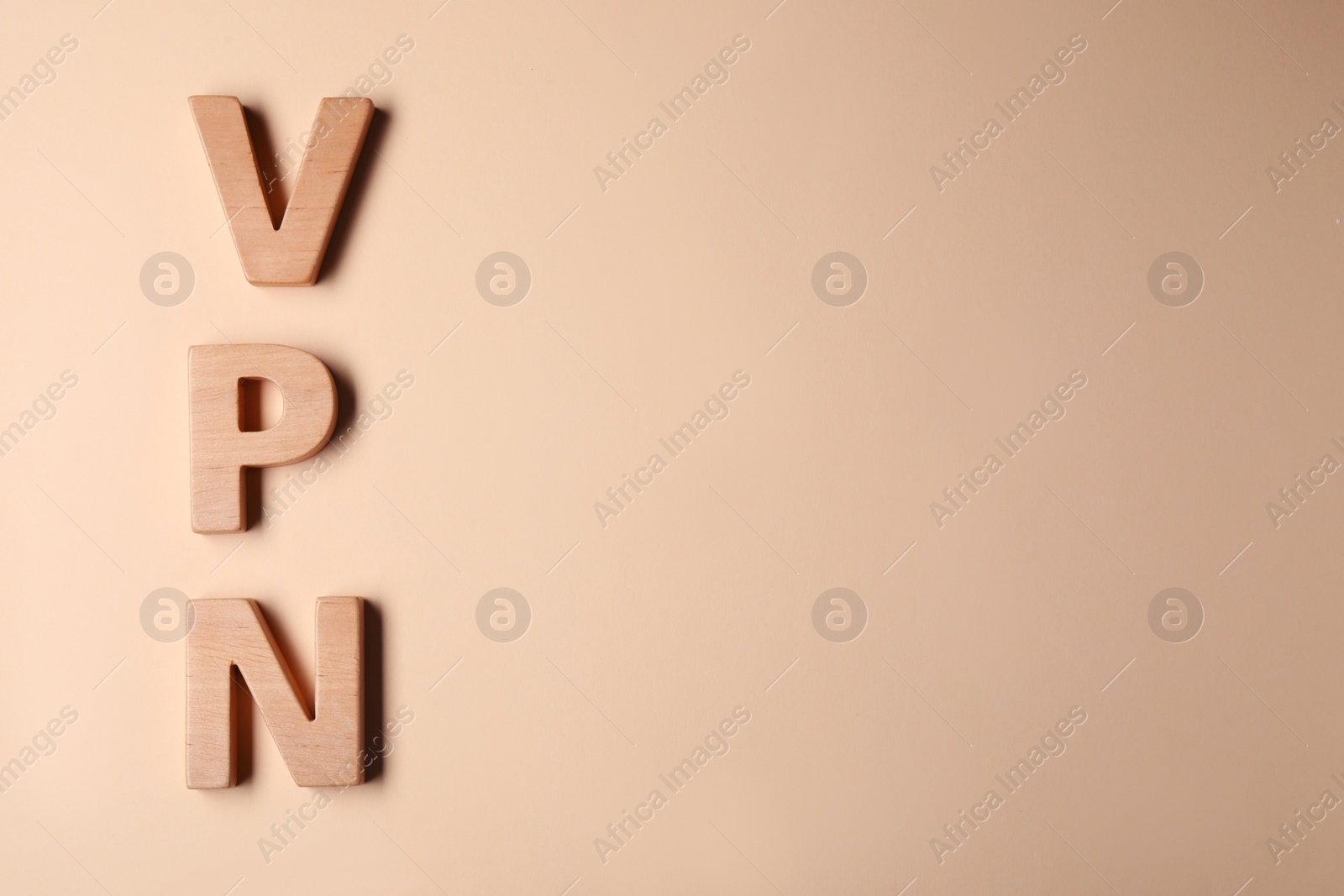 Photo of Acronym VPN made of wooden letters on beige background, flat lay. Space for text