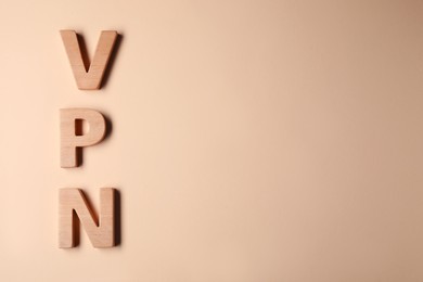 Photo of Acronym VPN made of wooden letters on beige background, flat lay. Space for text