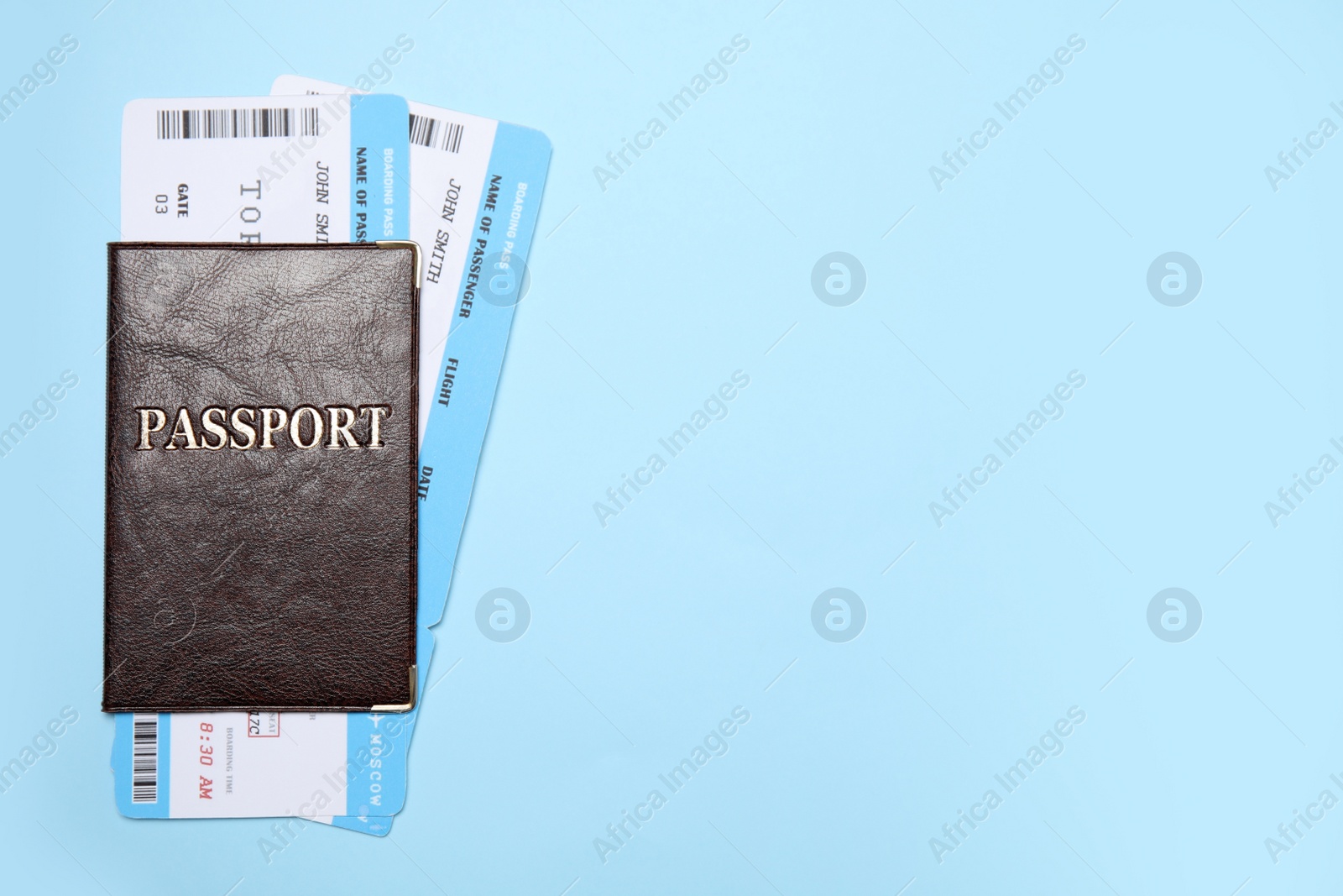 Photo of Passport with tickets on light blue background, top view. Space for text