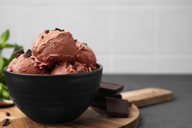 Photo of Bowl with tasty chocolate ice cream on grey wooden table, closeup. Space for text