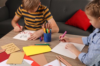 Photo of Children making beautiful greeting cards at table indoors