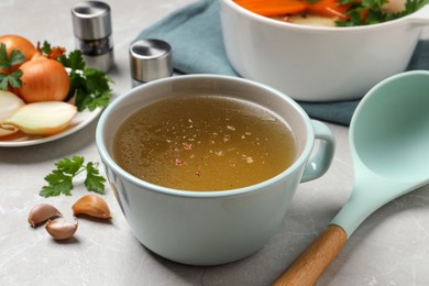 Photo of Hot delicious bouillon in cup on light grey table