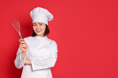 Photo of Happy confectioner holding whisk on red background, space for text
