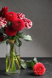 Photo of Beautiful dahlia flowers in vase on table against grey background