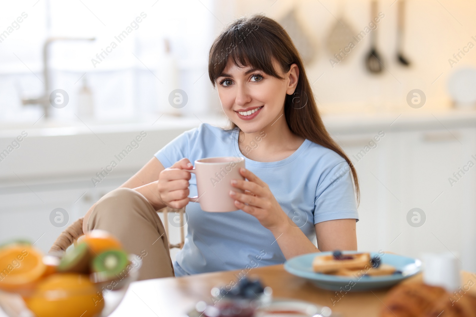 Photo of Smiling woman drinking coffee at breakfast indoors