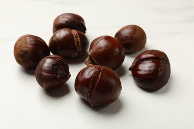 Roasted edible sweet chestnuts on white table, closeup