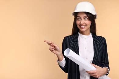 Architect in hard hat with draft pointing at something on beige background, space for text