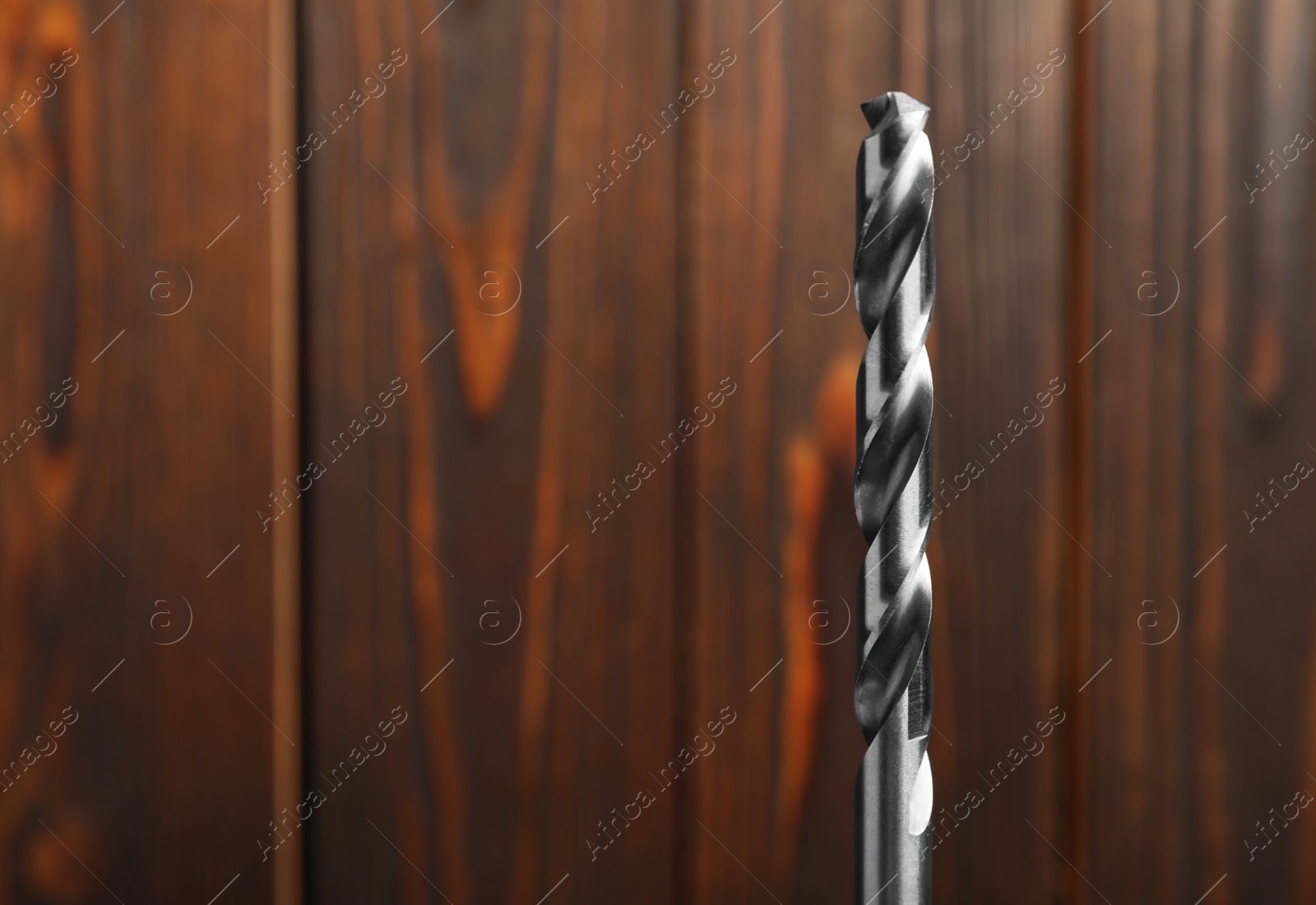 Photo of Closeup view of drill bit on wooden background. Space for text