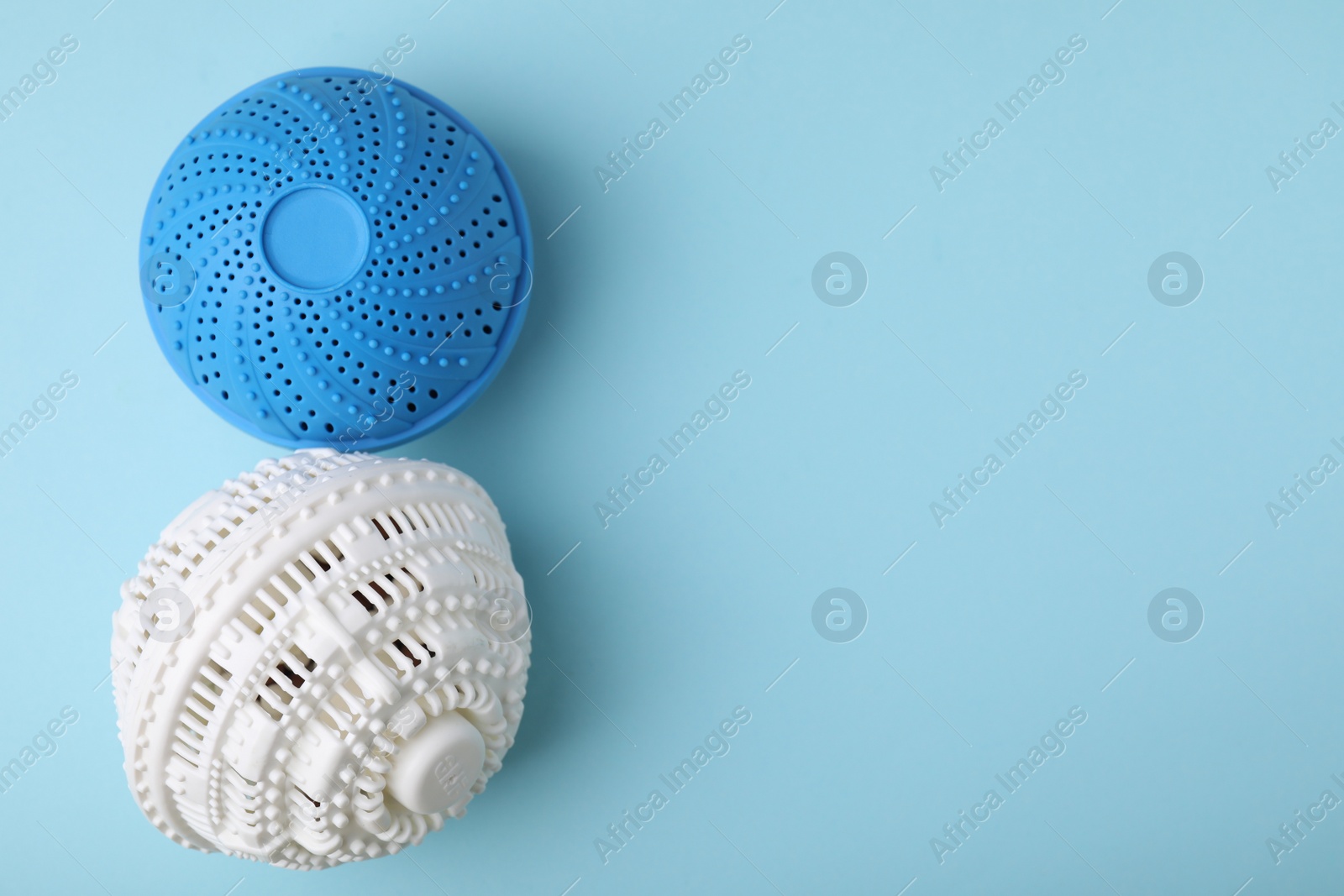 Photo of Laundry dryer balls on light blue background, flat lay. Space for text