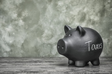 Photo of Black piggy bank with word TAXES on table