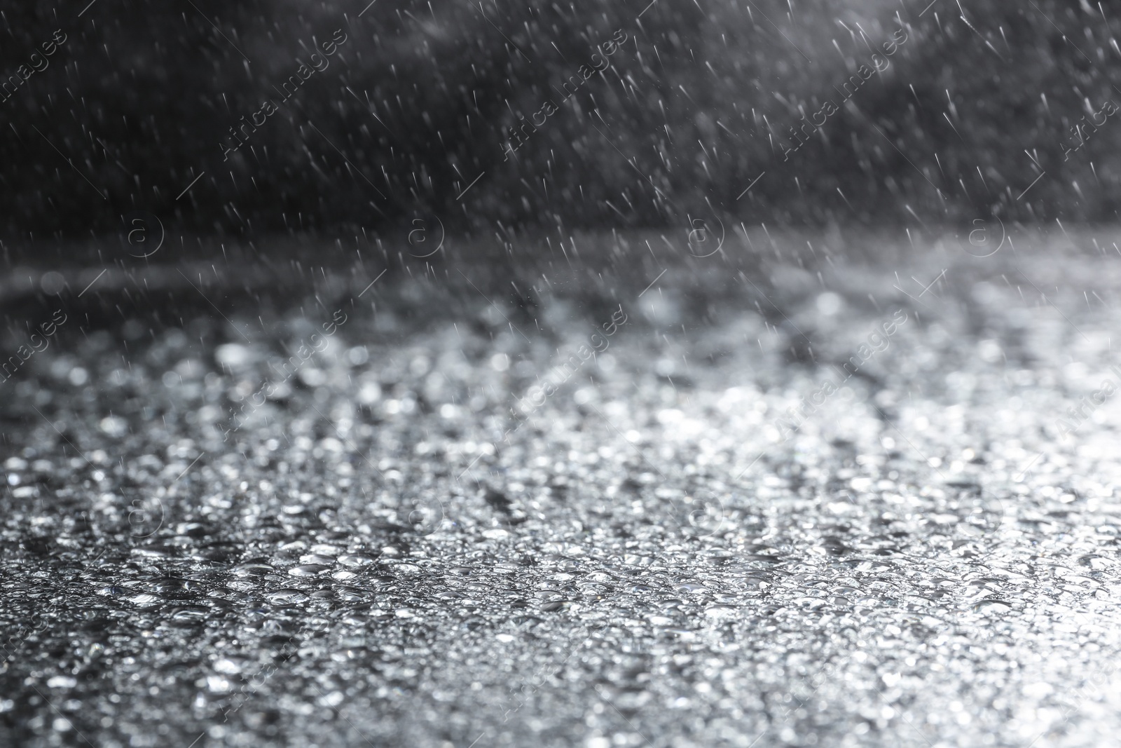 Photo of Rain drops falling down against dark background