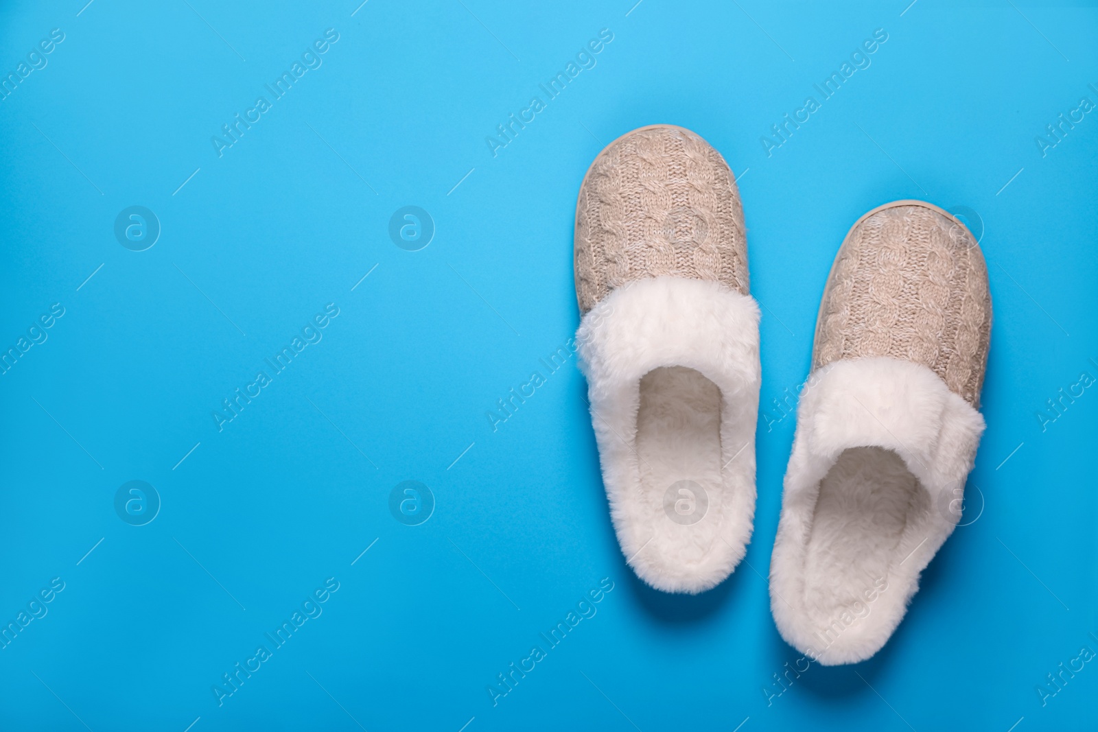 Photo of Pair of beautiful soft slippers on light blue background, top view. Space for text