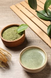 Photo of Cup of fresh matcha tea and green powder on wooden table