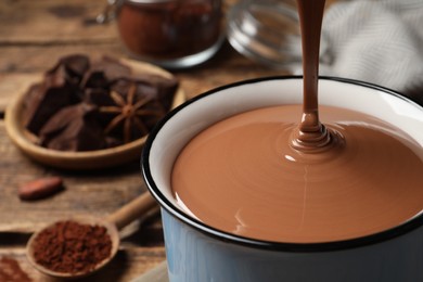 Photo of Pouring yummy hot chocolate into mug on table, closeup