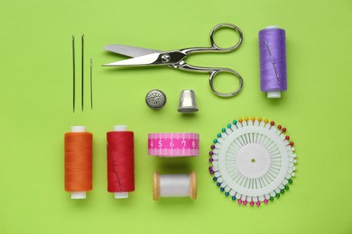 Photo of Flat lay composition with thimbles and different sewing tools on green background