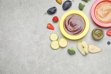 Healthy baby food and ingredients on grey table, flat lay. Space for text