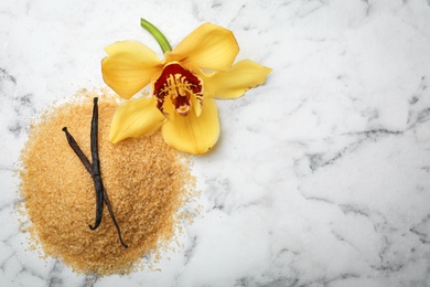 Photo of Aromatic vanilla sugar with flower and sticks on marble background