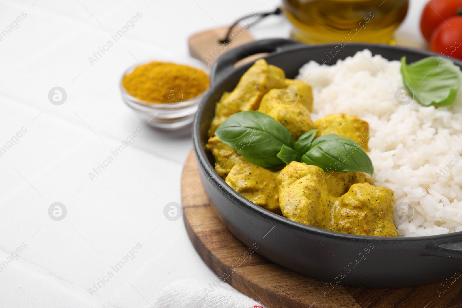 Photo of Delicious rice and chicken with curry sauce on white tiled table, closeup. Space for text