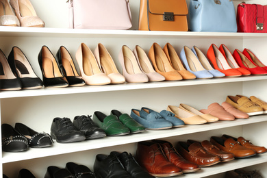 Photo of White shelving unit with different leather shoes and bags