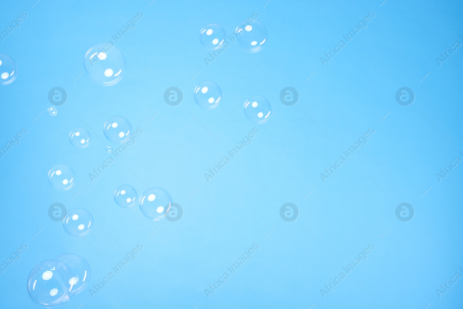 Photo of Many beautiful soap bubbles on light blue background. Space for text