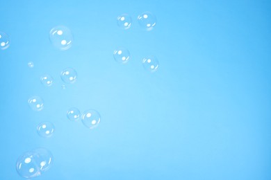 Photo of Many beautiful soap bubbles on light blue background. Space for text